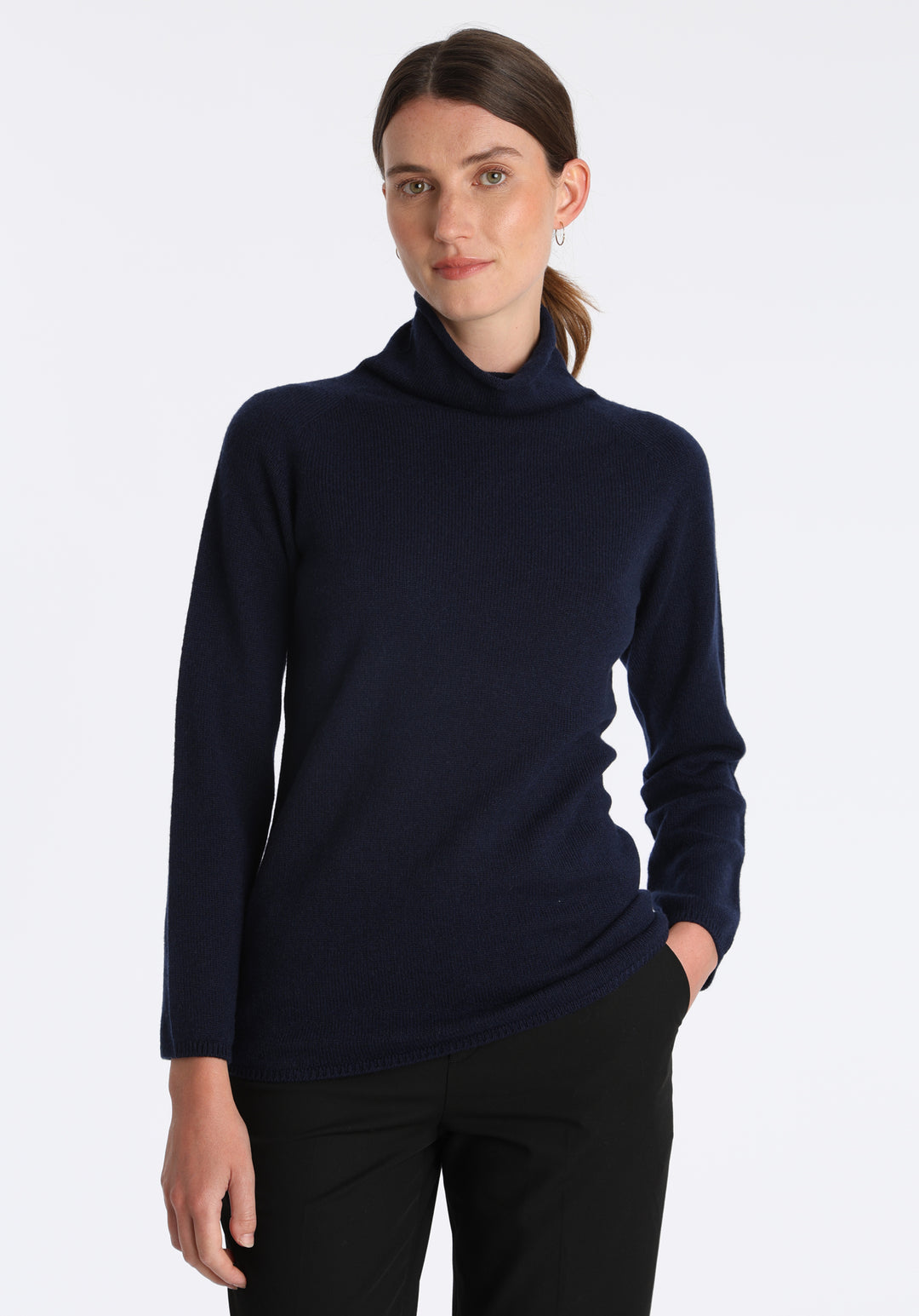 Model wearing the fine-knit cashmere jumper in navy, a slim fit style with a draped high neck, designed for layering and year-round wear.