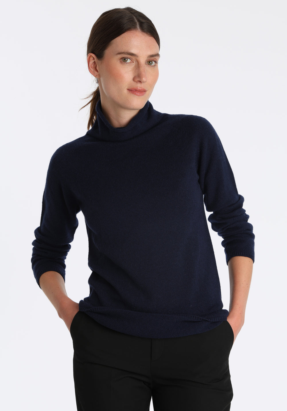 Model wearing the fine-knit cashmere jumper in navy, a slim fit style with a draped high neck, designed for layering and year-round wear.
