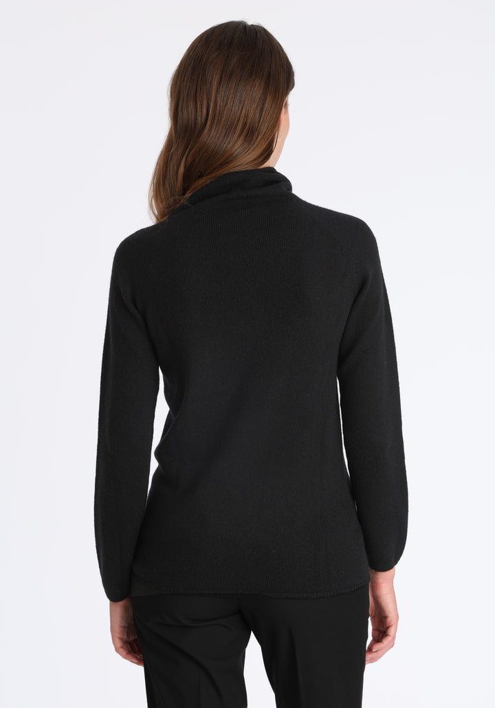 Model wearing the fine-knit cashmere jumper in black, a slim fit style with a draped high neck, designed for layering and year-round wear.