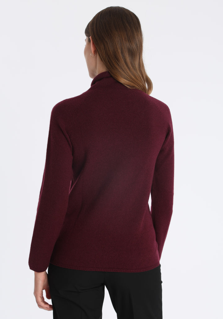 Model wearing the fine-knit cashmere jumper in shiraz, a slim fit style with a draped high neck, designed for layering and year-round wear.