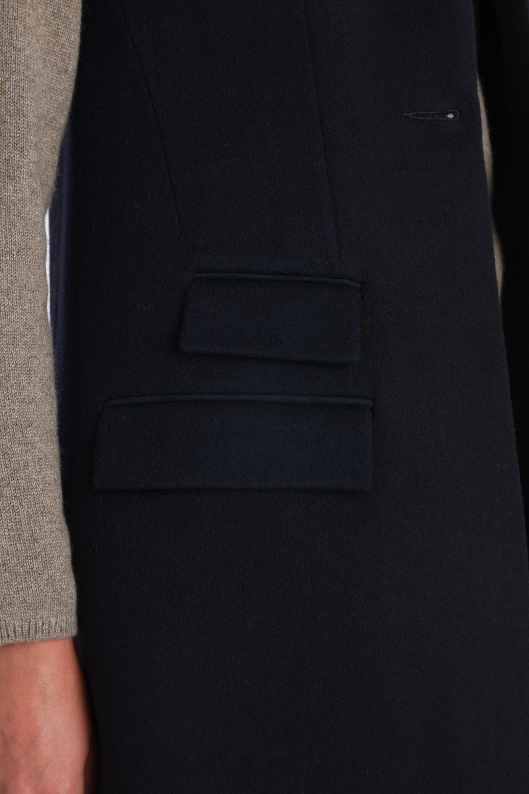 Model wearing the Kiekko waistcoat in navy merino wool with suede trim, a longline style featuring notched lapels, welt pockets, and a split back hem for ease of movement.