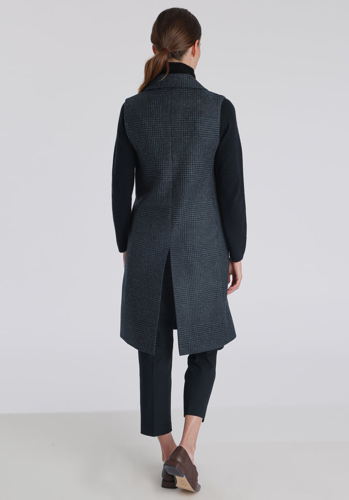 Model wearing the Kiekko waistcoat in black and grey Prince of Wales check with suede trim, a long line style featuring notched lapels, welt pockets, and a split back hem for ease of movement.