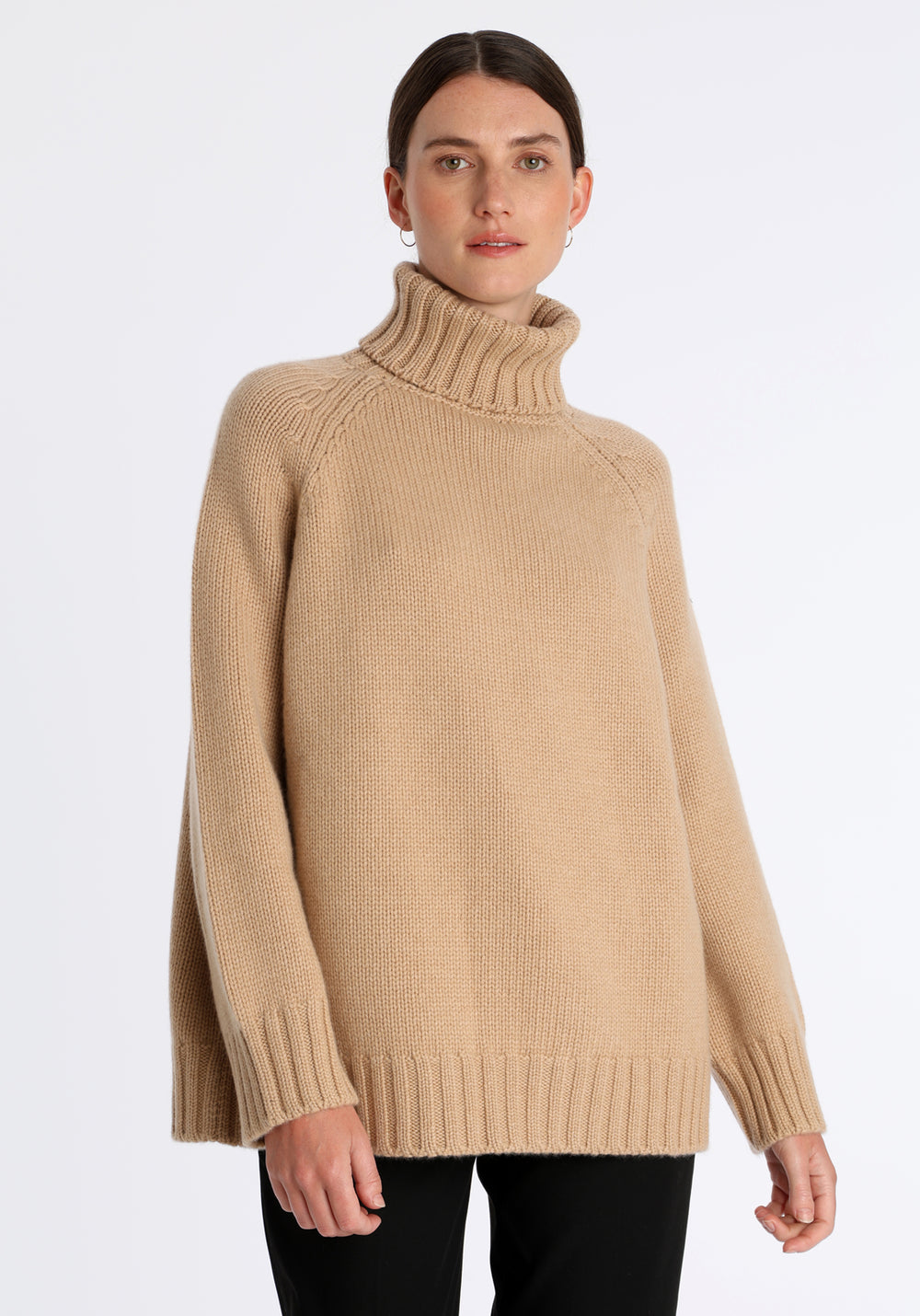 Model wearing the chunky roll neck jumper in dune Scottish cashmere—a one-size knit with dropped shoulders, ribbed trims, and a softly structured silhouette