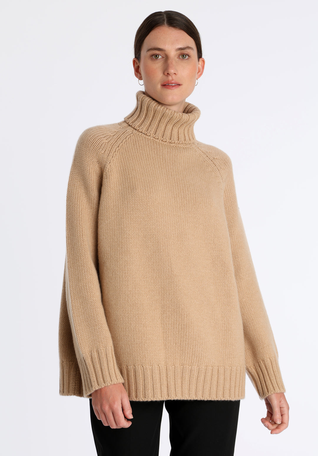 Model wearing the chunky roll neck jumper in dune Scottish cashmere—a one-size knit with dropped shoulders, ribbed trims, and a softly structured silhouette