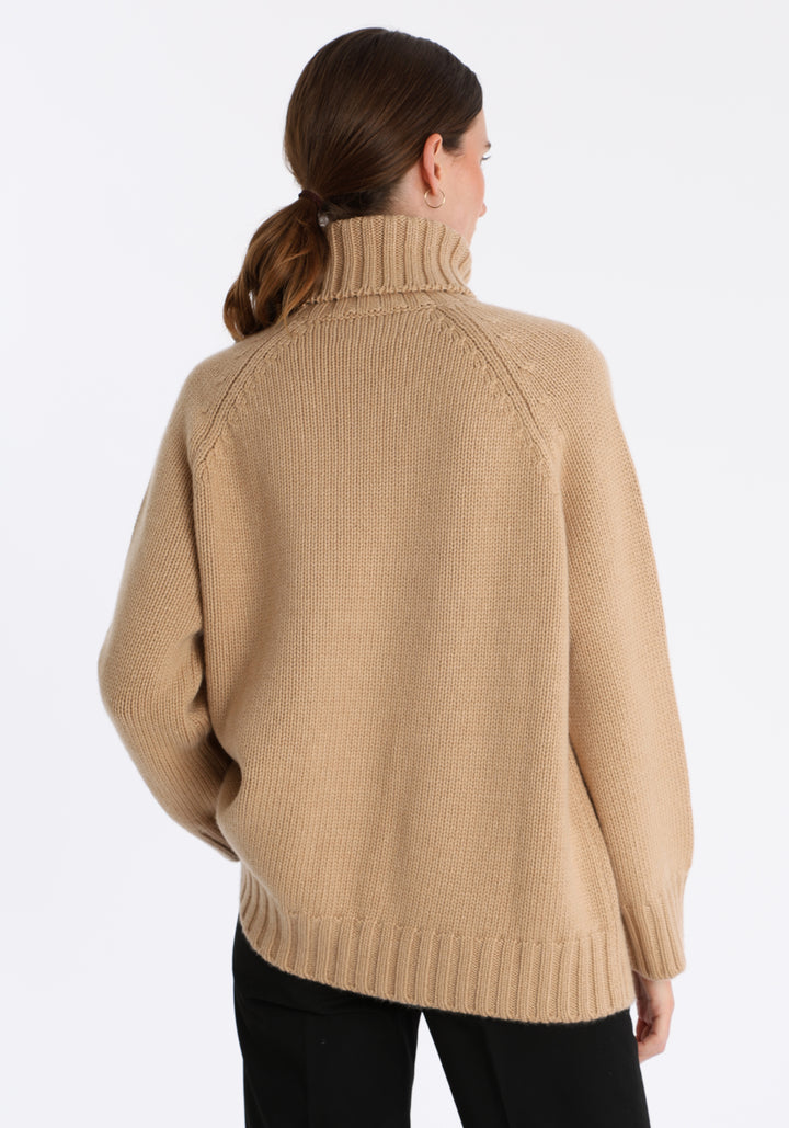 Model wearing the chunky roll neck jumper in dune Scottish cashmere—a one-size knit with dropped shoulders, ribbed trims, and a softly structured silhouette