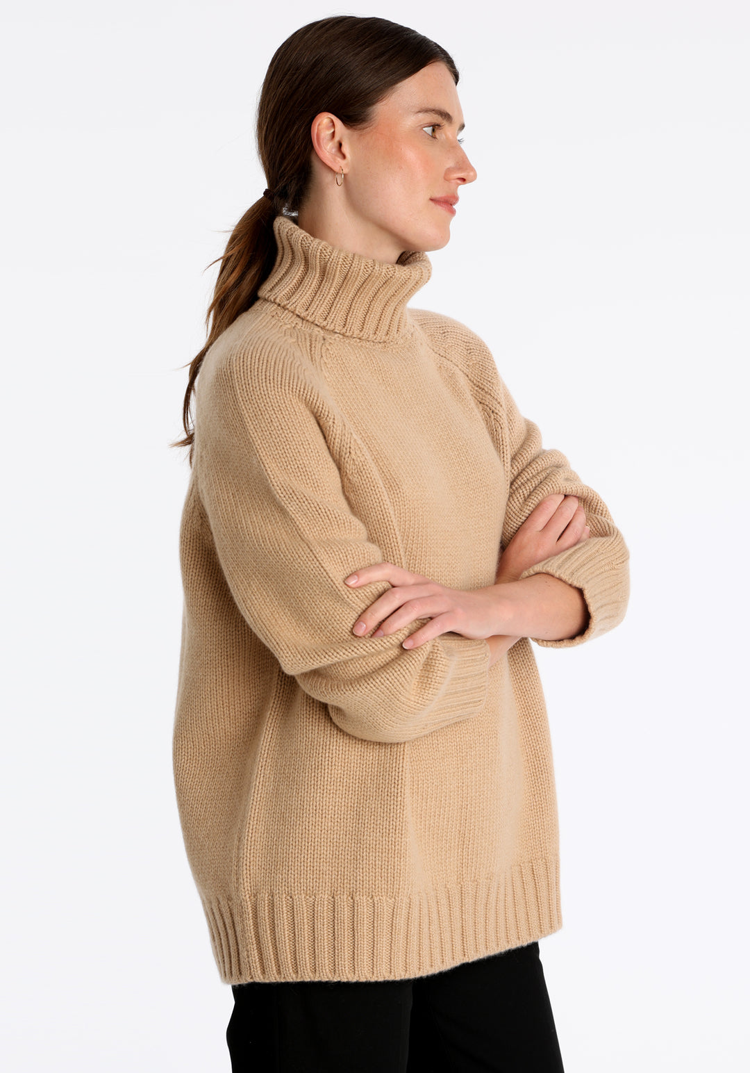 Model wearing the chunky roll neck jumper in dune Scottish cashmere—a one-size knit with dropped shoulders, ribbed trims, and a softly structured silhouette