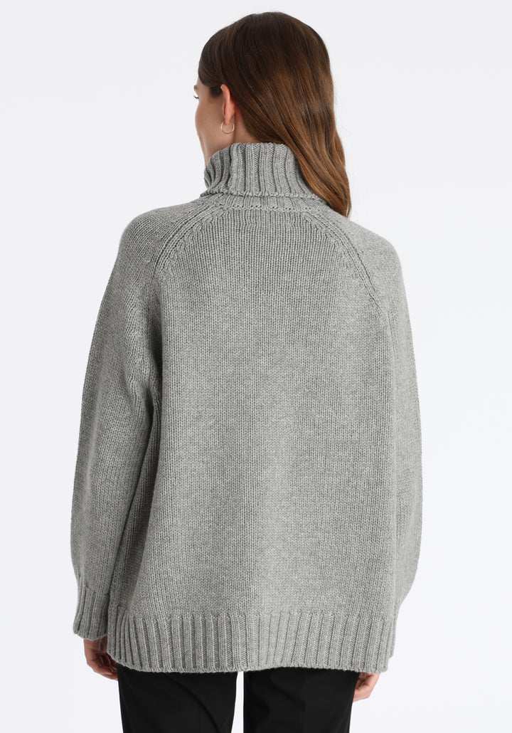Model wearing the chunky roll neck jumper in grey marl Scottish cashmere—a one-size knit with dropped shoulders, ribbed trims, and a softly structured silhouette.