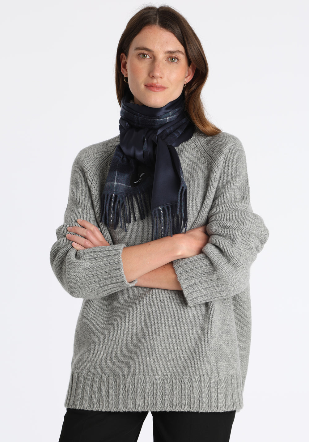 Model wearing the midnight check cashmere scarf backed with navy silk, over a chunky roll neck grey marl jumper.
