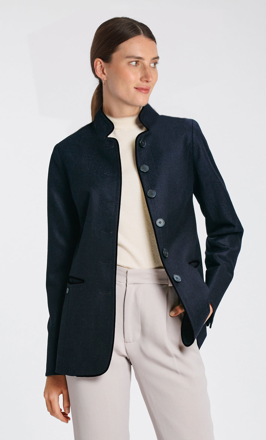 Model wearing the Patmos jacket in navy herringbone lambswool with short pile black cotton velvet trim, a slim-fit style featuring a mandarin collar, front pockets, and generous sleeves with slate button detailing.