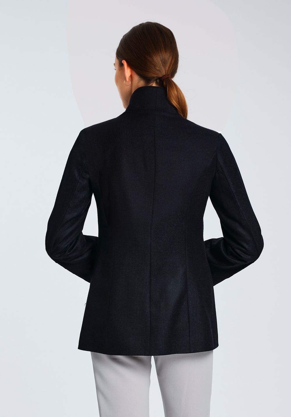 Model wearing the Patmos jacket in navy herringbone lambswool with short pile black cotton velvet trim, a slim-fit style featuring a mandarin collar, front pockets, and generous sleeves with slate button detailing.