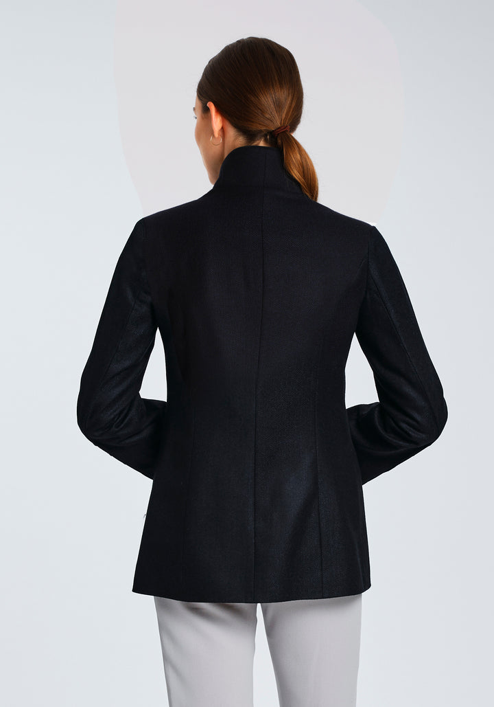 Model wearing the Patmos jacket in navy herringbone lambswool with short pile black cotton velvet trim, a slim-fit style featuring a mandarin collar, front pockets, and generous sleeves with slate button detailing.