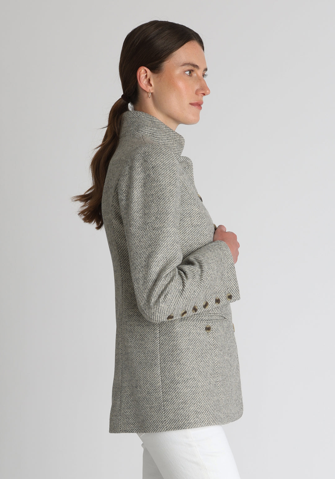Model wearing the Patmos jacket in slate blue and cream lambswool wool with suede trim, a slim-fit style featuring a mandarin collar, front pockets, and generous sleeves with button detailing.
