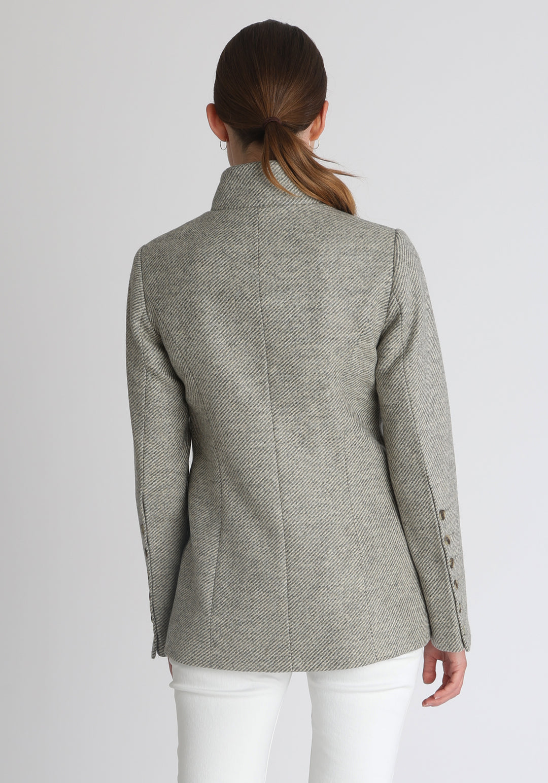 Model wearing the Patmos jacket in slate blue and cream lambswool wool with suede trim, a slim-fit style featuring a mandarin collar, front pockets, and generous sleeves with button detailing.