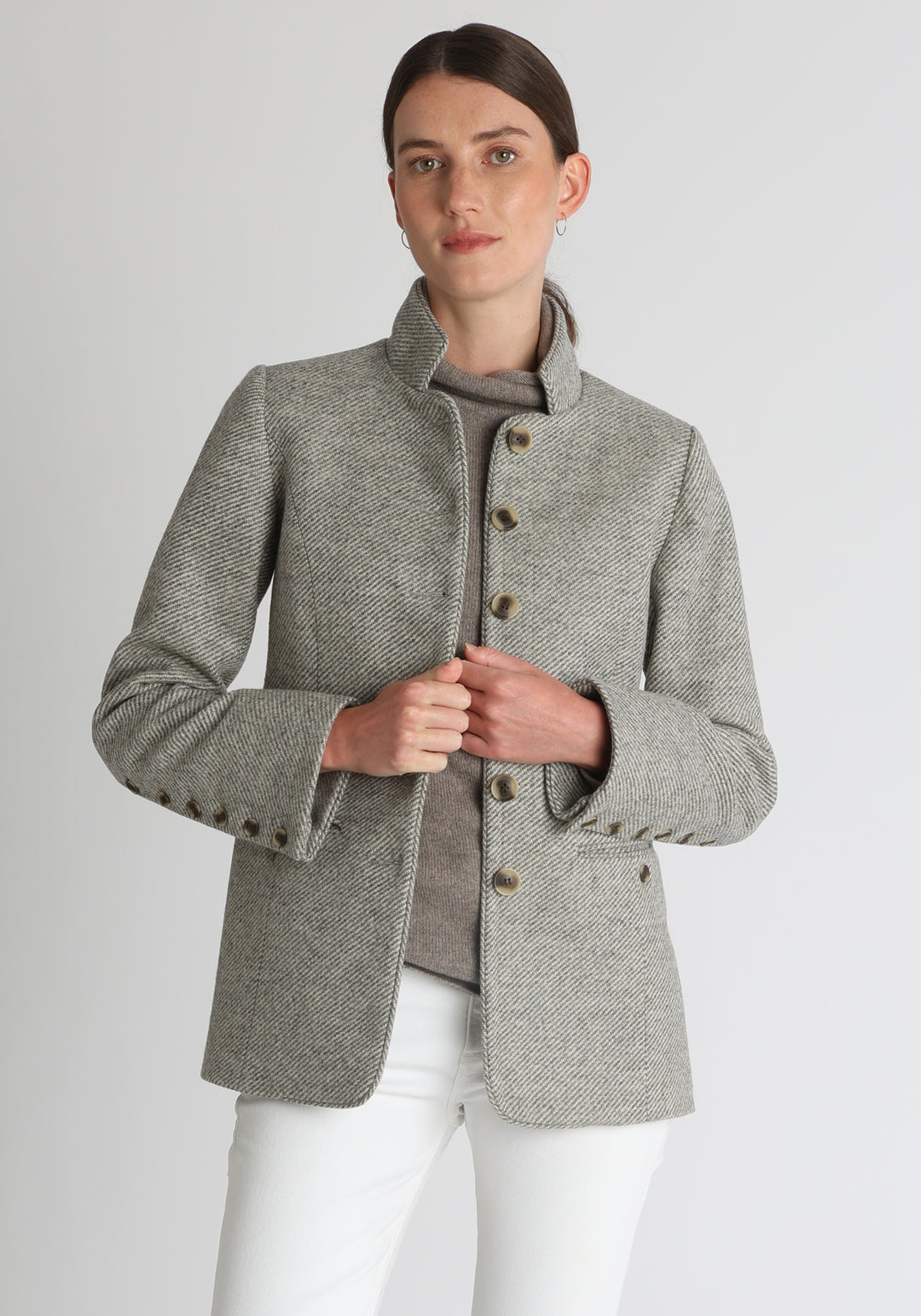 Model wearing the Patmos jacket in slate blue and cream lambswool wool with suede trim, a slim-fit style featuring a mandarin collar, front pockets, and generous sleeves with button detailing.