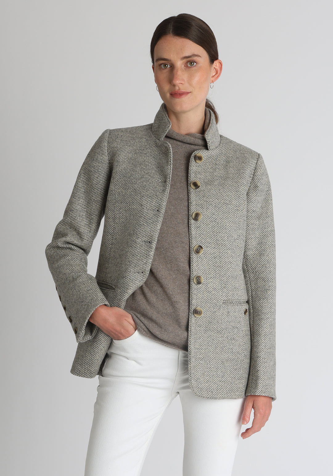 Model wearing the Patmos jacket in slate blue and cream lambswool wool with suede trim, a slim-fit style featuring a mandarin collar, front pockets, and generous sleeves with button detailing.