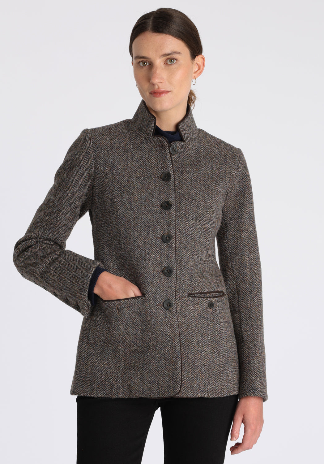 Model wearing the Patmos jacket in heather herringbone Harris Tweed with suede trim, a slim-fit style featuring a mandarin collar, front pockets, and generous sleeves with button detailing.