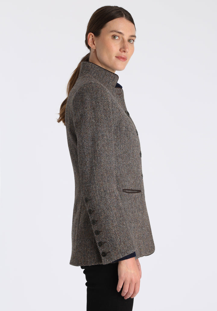 Model wearing the Patmos jacket in heather herringbone Harris Tweed with suede trim, a slim-fit style featuring a mandarin collar, front pockets, and generous sleeves with button detailing.