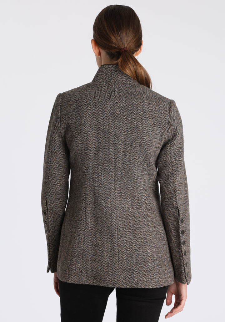 Model wearing the Patmos jacket in heather herringbone Harris Tweed with suede trim, a slim-fit style featuring a mandarin collar, front pockets, and generous sleeves with button detailing.