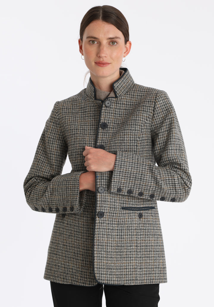 Model wearing the Patmos jacket in stone grey and ochre check with suede trim, a slim-fit style featuring a mandarin collar, front pockets, and generous sleeves with button detailing.