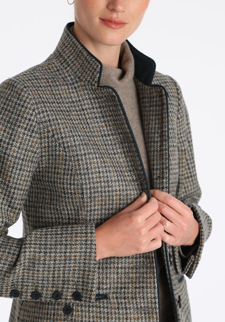 Model wearing the Patmos jacket in stone grey and ochre check with suede trim, a slim-fit style featuring a mandarin collar, front pockets, and generous sleeves with button detailing.