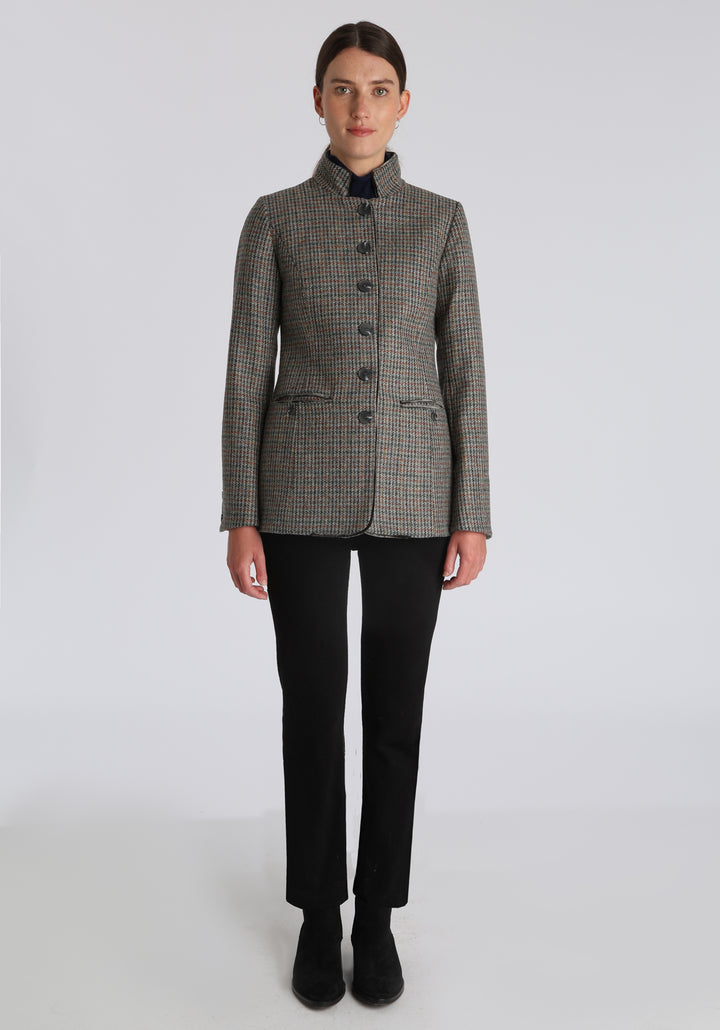 Model wearing the Patmos jacket in autumnal cinder dogtooth check with silk velvet trim, a slim-fit style featuring a mandarin collar, front pockets, and generous sleeves with slate button detailing.
