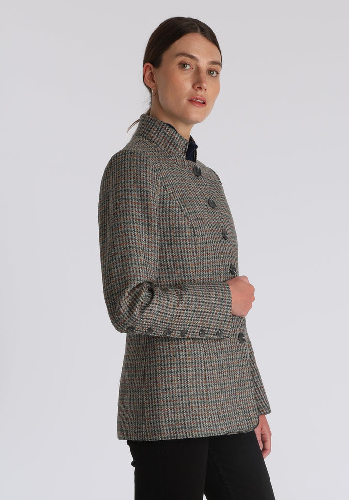 Model wearing the Patmos jacket in autumnal cinder dogtooth check with silk velvet trim, a slim-fit style featuring a mandarin collar, front pockets, and generous sleeves with slate button detailing.
