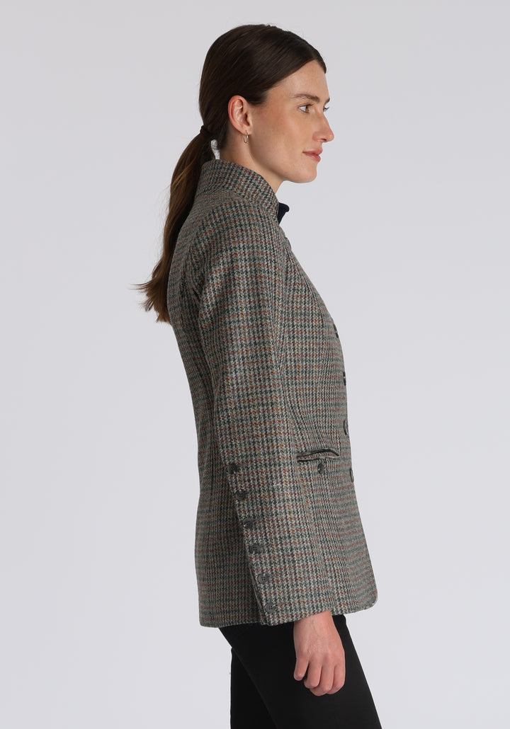 Model wearing the Patmos jacket in autumnal cinder dogtooth check with silk velvet trim, a slim-fit style featuring a mandarin collar, front pockets, and generous sleeves with slate button detailing.