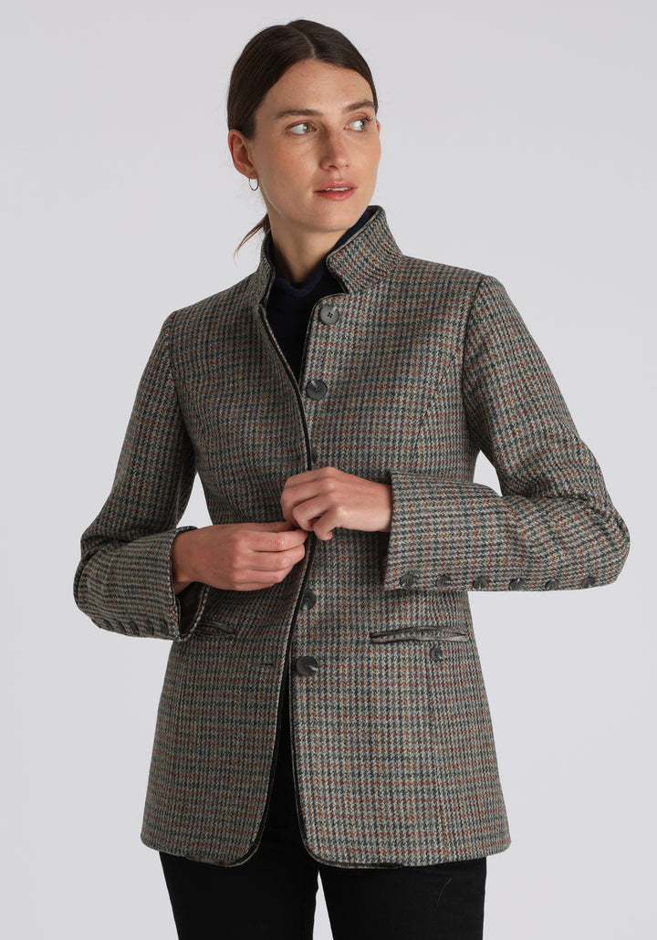 Model wearing the Patmos jacket in autumnal cinder dogtooth check with silk velvet trim, a slim-fit style featuring a mandarin collar, front pockets, and generous sleeves with slate button detailing.