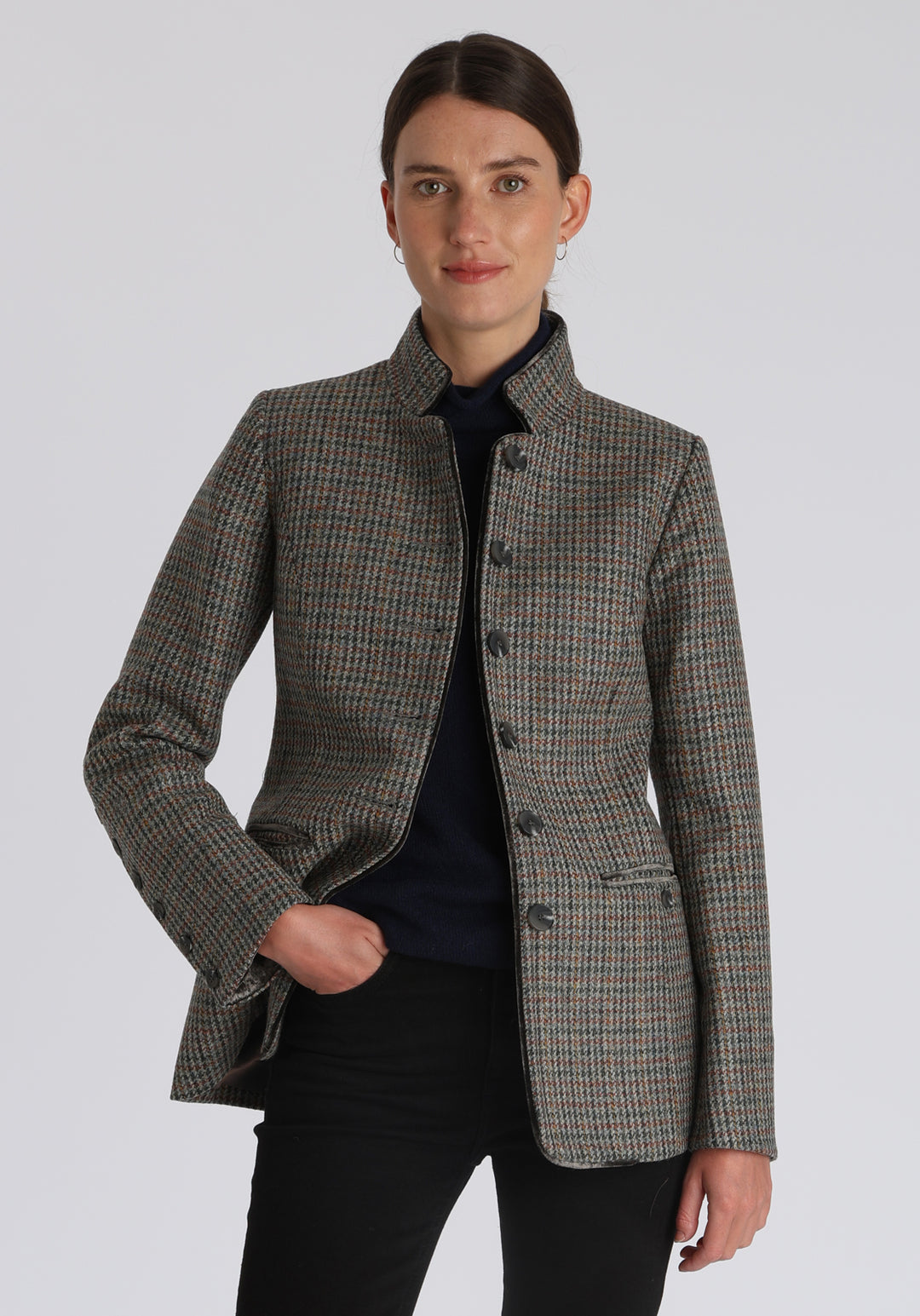Model wearing the Patmos jacket in autumnal cinder dogtooth check with silk velvet trim, a slim-fit style featuring a mandarin collar, front pockets, and generous sleeves with slate button detailing.