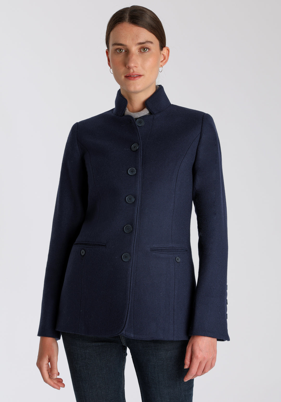 Model wearing the Patmos jacket in textured navy merino wool with suede trim, a slim-fit style featuring a mandarin collar, front pockets, and generous sleeves with button detailing.