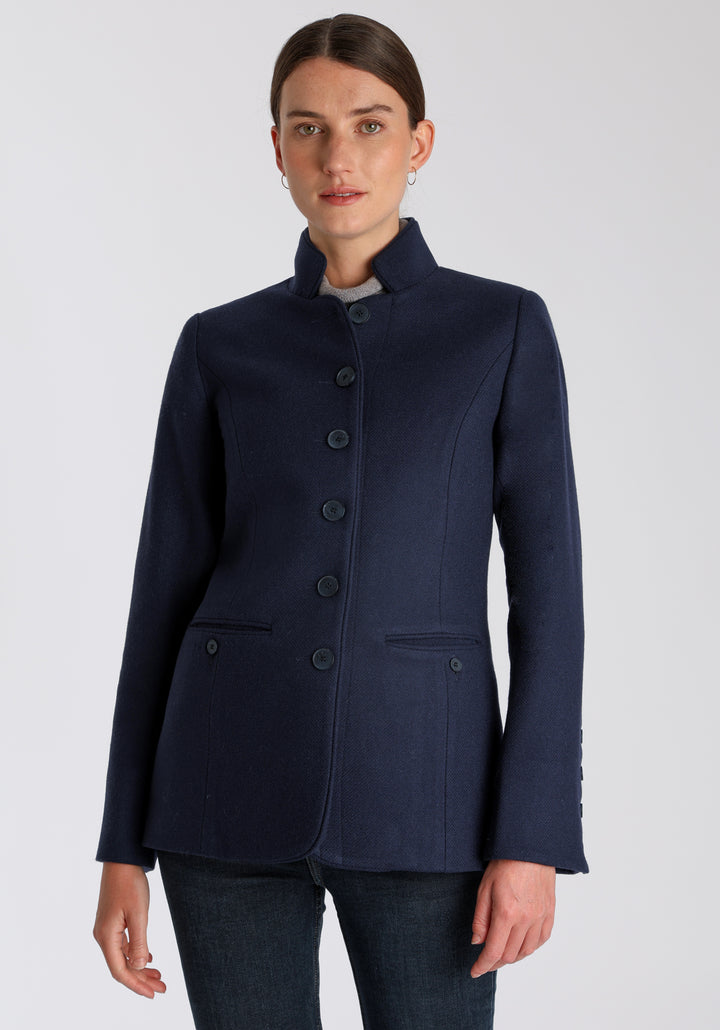 Model wearing the Patmos jacket in textured navy merino wool with suede trim, a slim-fit style featuring a mandarin collar, front pockets, and generous sleeves with button detailing.