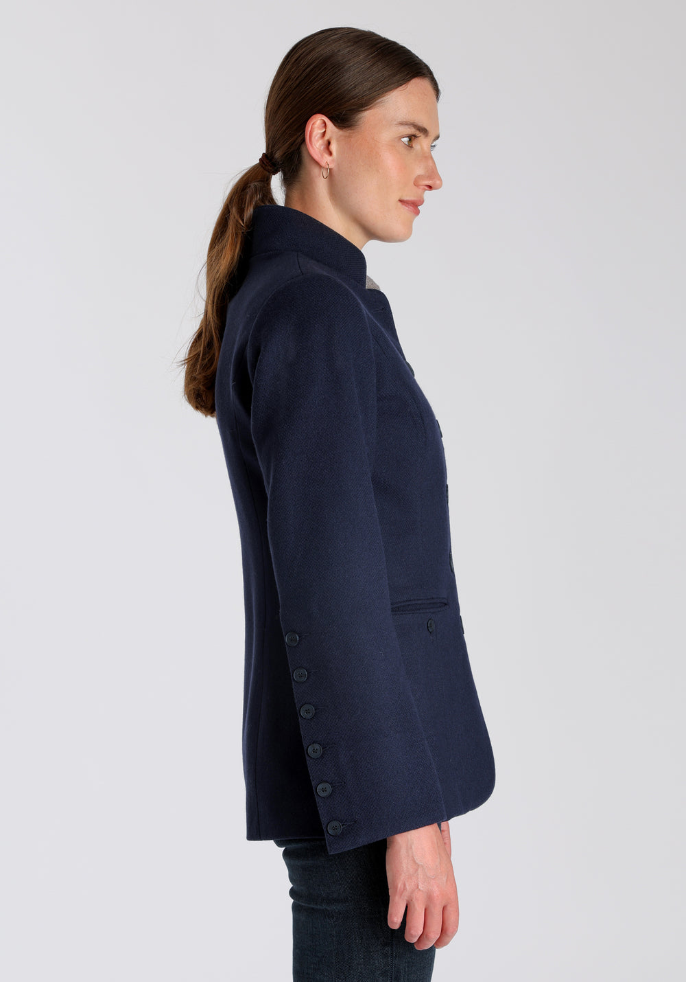Model wearing the Patmos jacket in textured navy merino wool with suede trim, a slim-fit style featuring a mandarin collar, front pockets, and generous sleeves with button detailing.