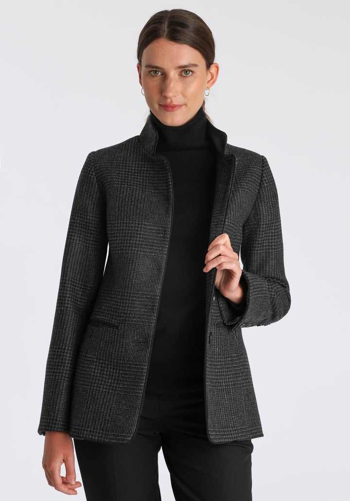 Model wearing the Patmos jacket in black and grey Prince of Wales check with suede trim, a slim-fit style featuring a mandarin collar, front pockets, and generous sleeves with slate button detailing.