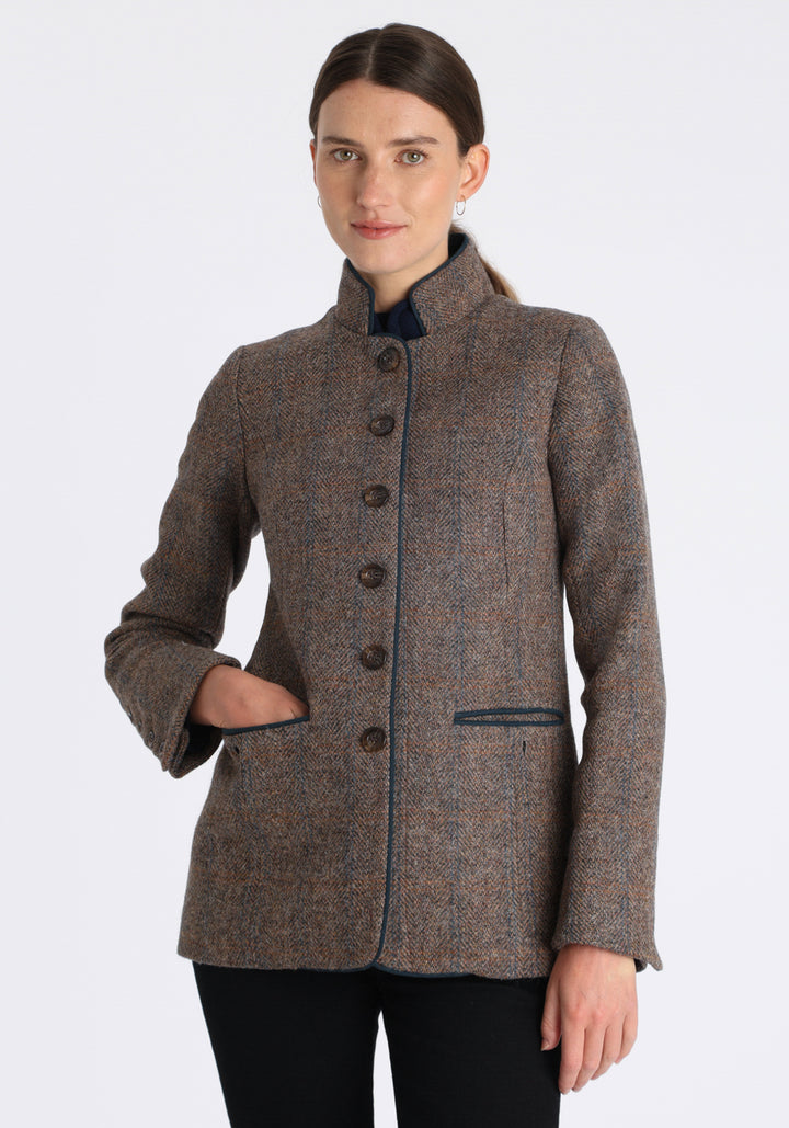 Model wearing the Patmos jacket in a Harris Tweed Clay check, with peach, grey, and brown tones, it features petrol blue suede detailing, a slim fit style featuring a mandarin collar, front pockets, and generous sleeves with button detailing.