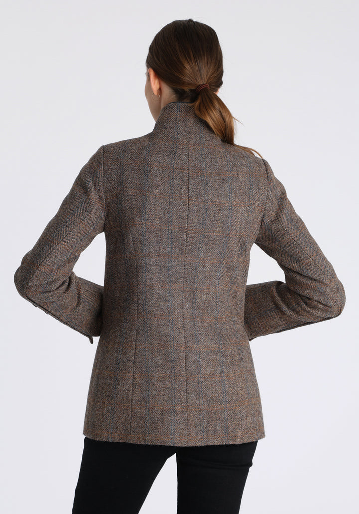 Model wearing the Patmos jacket in a Harris Tweed Clay check, with peach, grey, and brown tones, it features petrol blue suede detailing, a slim fit style featuring a mandarin collar, front pockets, and generous sleeves with button detailing.