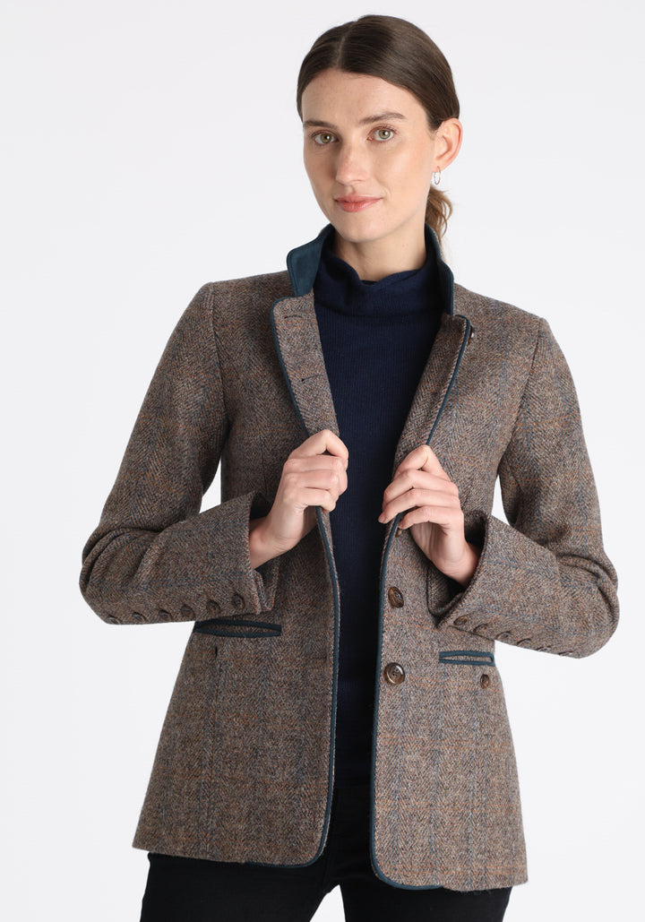 Model wearing the Patmos jacket in a Harris Tweed Clay check, with peach, grey, and brown tones, it features petrol blue suede detailing, a slim fit style featuring a mandarin collar, front pockets, and generous sleeves with button detailing.