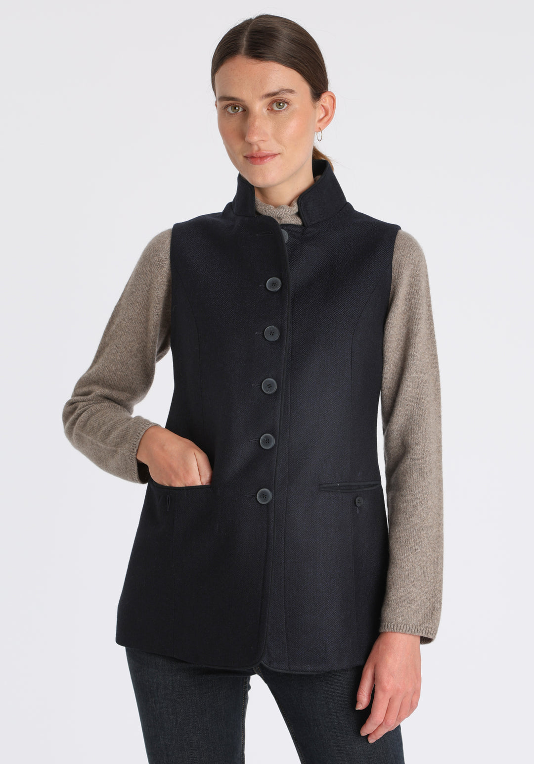 Model wearing the Patmos waistcoat in navy herringbone lambswool with suede trim, a longline, neatly tailored style with a mandarin collar.
