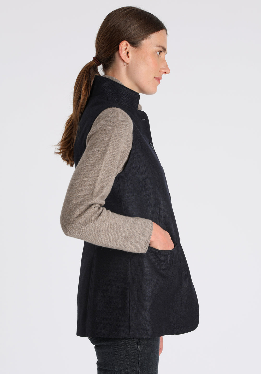Model wearing the Patmos waistcoat in navy herringbone lambswool with suede trim, a longline, neatly tailored style with a mandarin collar.