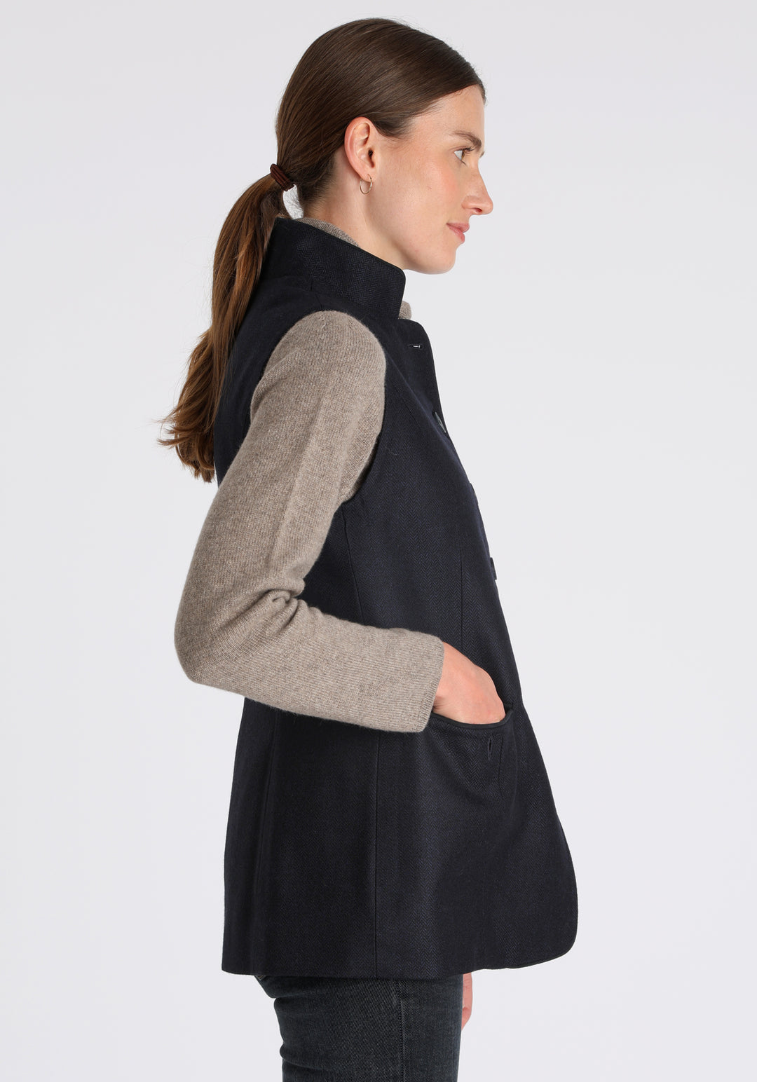 Model wearing the Patmos waistcoat in navy herringbone lambswool with suede trim, a longline, neatly tailored style with a mandarin collar.