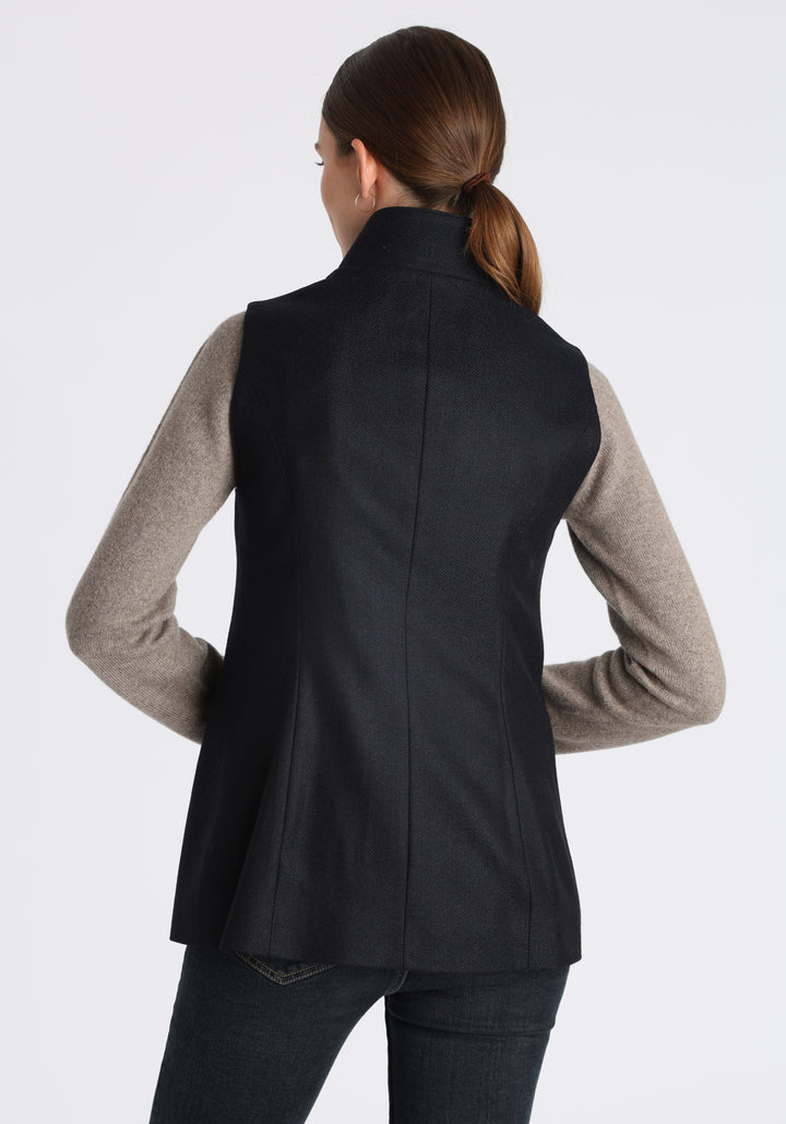 Model wearing the Patmos waistcoat in navy herringbone lambswool with suede trim, a longline, neatly tailored style with a mandarin collar.