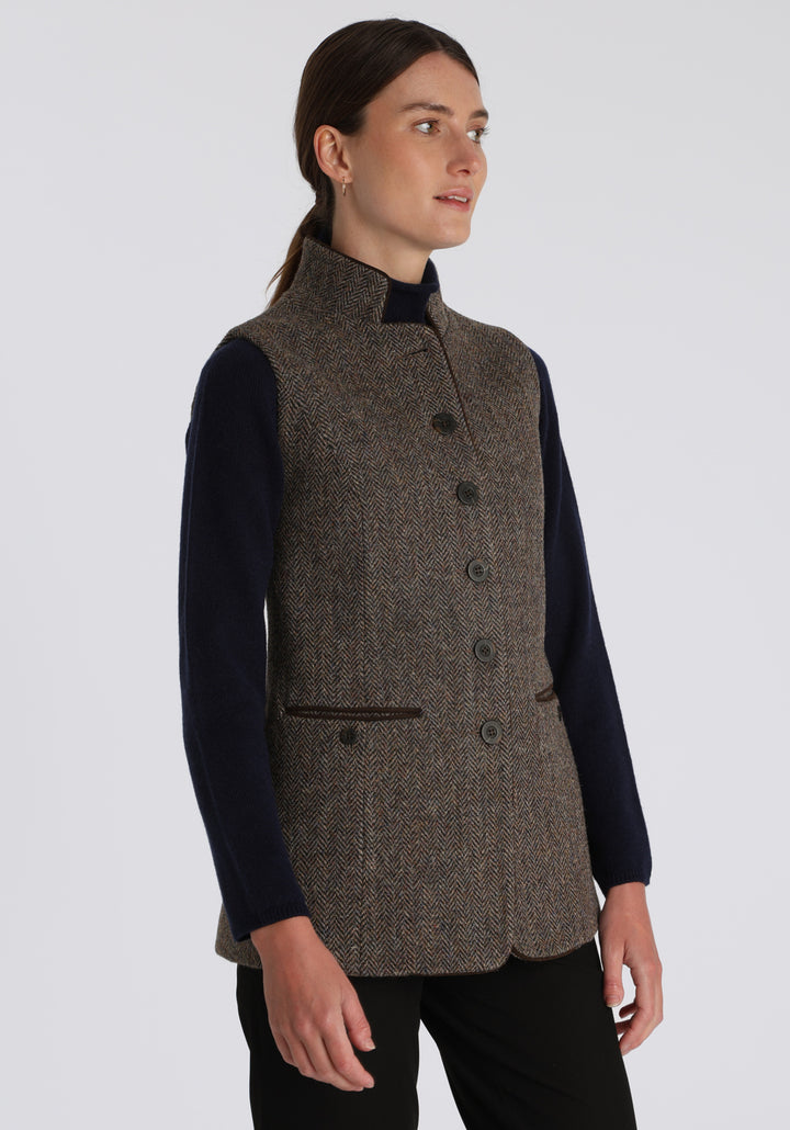 Model wearing the Patmos waistcoat in heather herringbone Harris Tweed with suede trim, a longline, neatly tailored style with a mandarin collar.