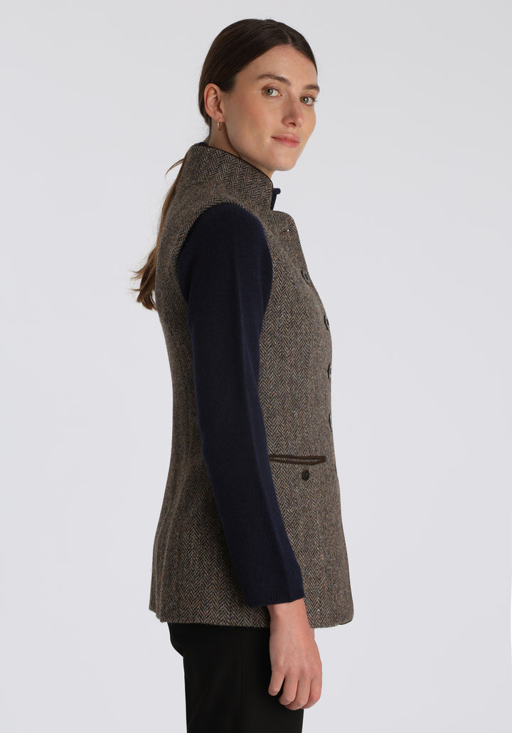 Model wearing the Patmos waistcoat in heather herringbone Harris Tweed with suede trim, a longline, neatly tailored style with a mandarin collar.