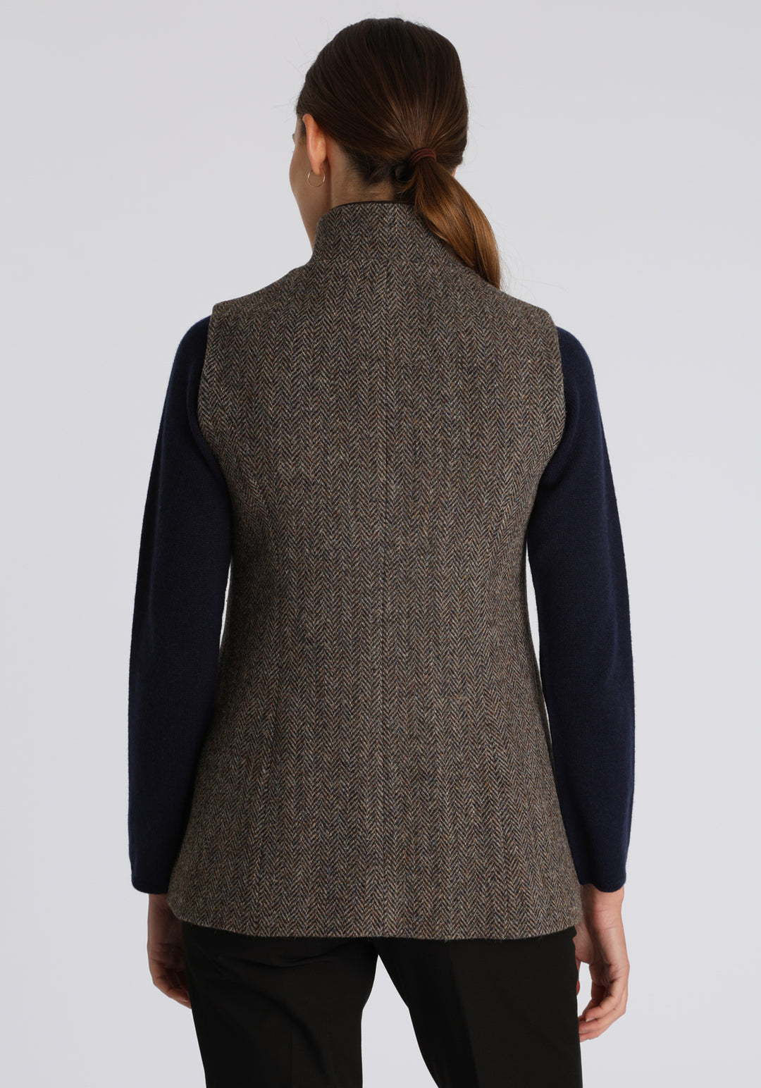 Model wearing the Patmos waistcoat in heather herringbone Harris Tweed with suede trim, a longline, neatly tailored style with a mandarin collar.