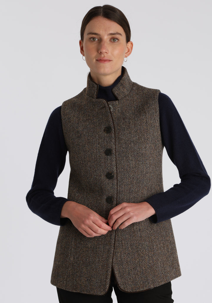Model wearing the Patmos waistcoat in heather herringbone Harris Tweed with suede trim, a longline, neatly tailored style with a mandarin collar.
