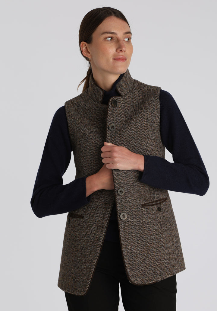 Model wearing the Patmos waistcoat in heather herringbone Harris Tweed with suede trim, a longline, neatly tailored style with a mandarin collar.