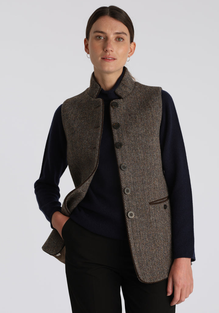 Model wearing the Patmos waistcoat in heather herringbone Harris Tweed with suede trim, a longline, neatly tailored style with a mandarin collar.