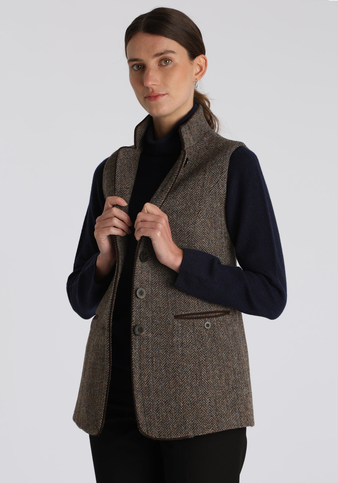 Model wearing the Patmos waistcoat in heather herringbone Harris Tweed with suede trim, a longline, neatly tailored style with a mandarin collar.