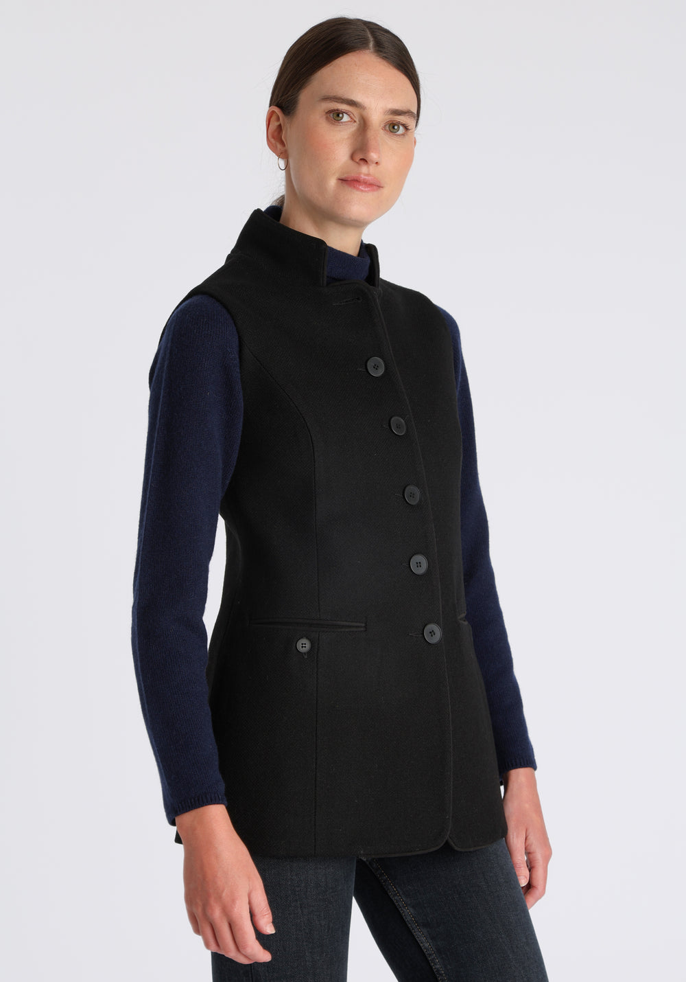 Model wearing the Patmos waistcoat in black textured merino wool with suede trim, a longline, neatly tailored style with a mandarin collar.