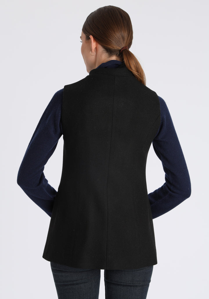 Model wearing the Patmos waistcoat in black textured merino wool with suede trim, a longline, neatly tailored style with a mandarin collar.