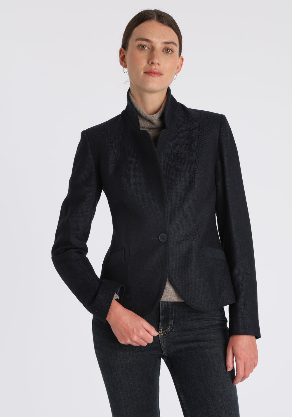 Model wearing the Tallulah jacket in navy herringbone lambswool with suede trim, a tailored style with a single button fastening and a collar that can be worn turned up or down.
